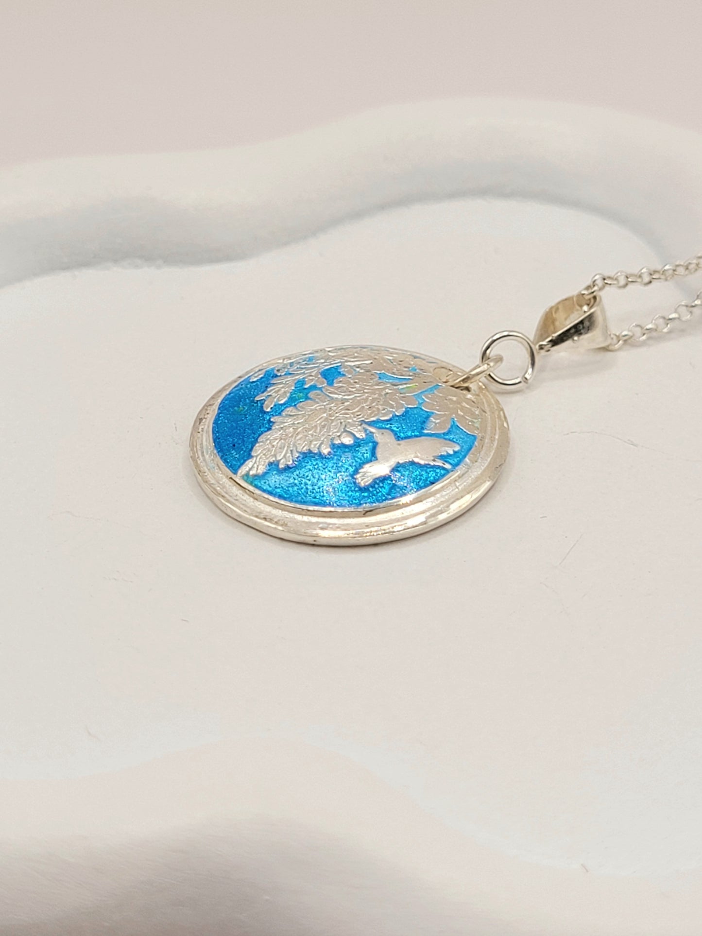 gros plan sur le pendentif champlevé en émail sur argent fin représentant un papillon sphynx dans les glycines. Emaux translucides. Bijou artisanal maison Calub les émaux du luberon made in France