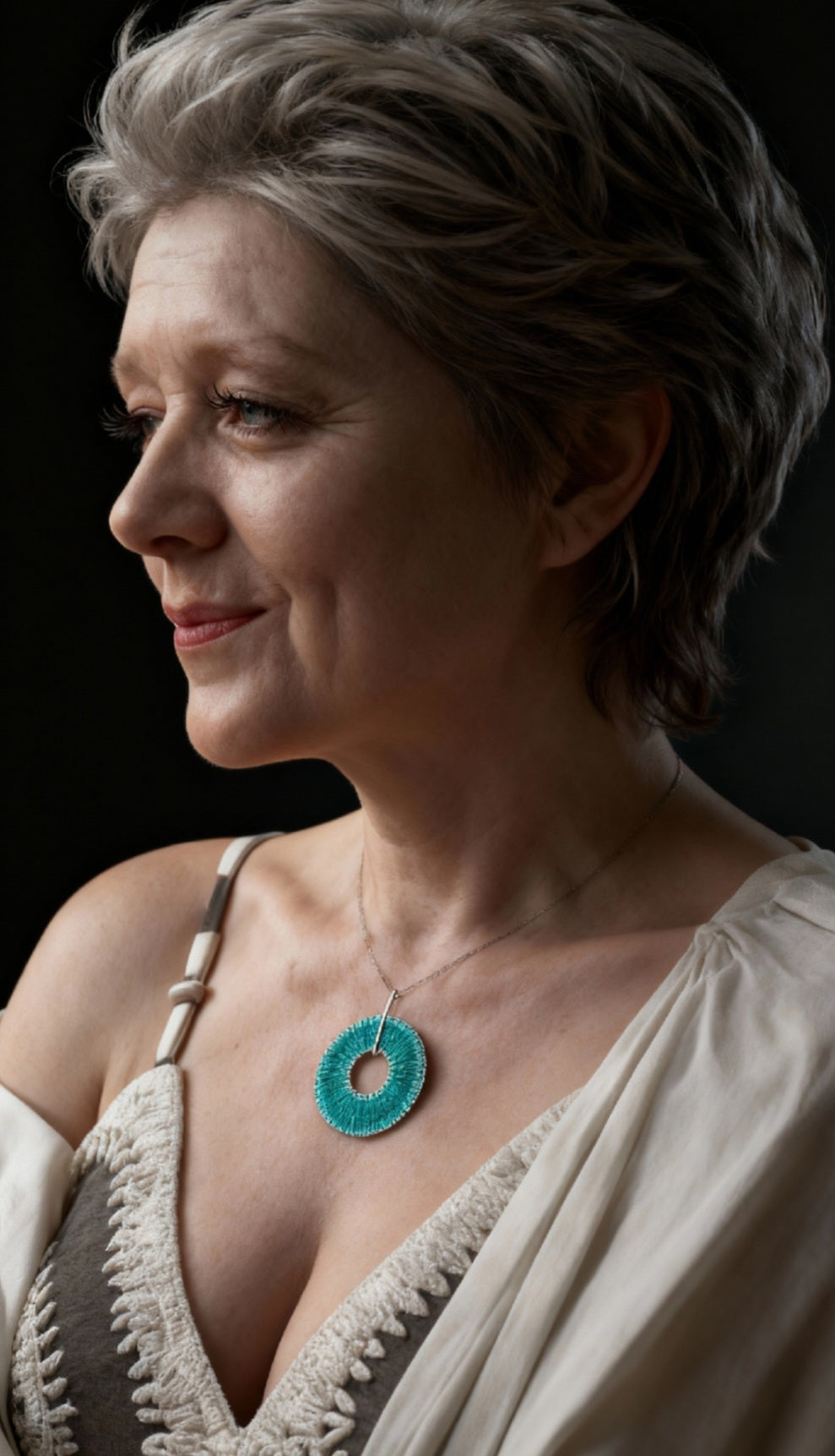 femme montrant son  pendentif ROUE émail basse-taille sur argent fin de couleur turquoise -  maison CALUB émaux du Luberon. bijou artisanal en émail grand feu.