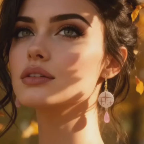 video présentant des boucles d'oreilles en émail sur cuivre aux motif d'étoiles rosés sur blanc prolongé par une perle de verre goutte. Bijou artisanal fait à la main chez maison calub les emaux du Luberon