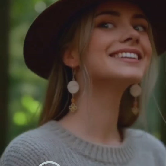 vidéo d'une jeune femme portant les boucles d'oreilles en émail sur cuivre - bijou artisanal français évoquant la silhouette de la montagne sainte victoire à Aix-en-Provence, d'une simple ligne noire sur fond blanc.Breloque dorée et perle en verre